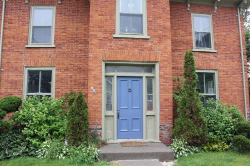 a brick building with a blue door in front at County Cove - Picton Suite in Wellington