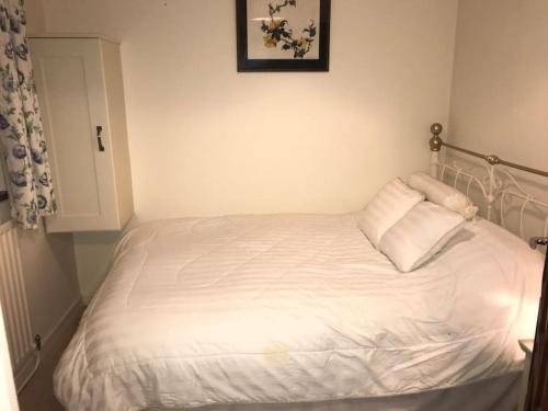 a white bed in a bedroom with a picture on the wall at Four Winds, Ross, Killala. in Killala