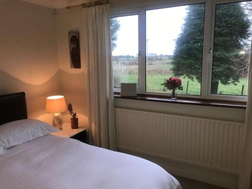 a bedroom with a bed and a window with a view at Four Winds, Ross, Killala. in Killala