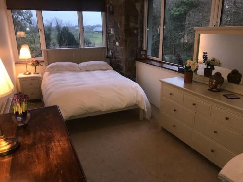 a bedroom with a bed and a table and windows at Four Winds, Ross, Killala. in Killala