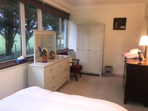 a bedroom with a bed and a dresser and windows at Four Winds, Ross, Killala. in Killala