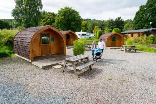 a man and a woman walking in front of a cabin at Lomond Woods Holiday Park in Balloch