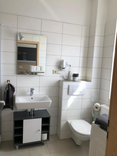 a white bathroom with a toilet and a sink at Ferienwohnung Spremberg-City II in Spremberg