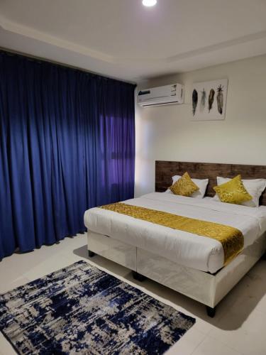 a bedroom with a large bed with blue curtains at Al Mabeet 2 Hotel suites in Abha