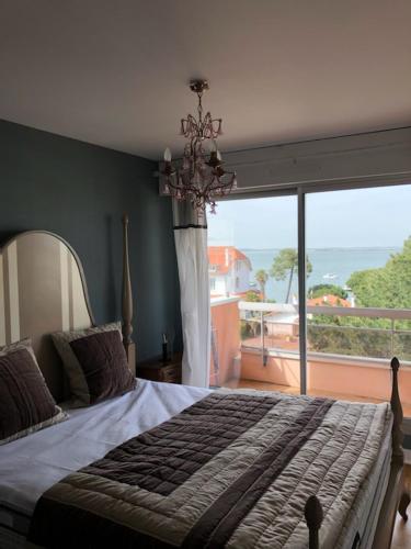 une chambre avec un grand lit et une grande fenêtre dans l'établissement APPT T2 AVEC VUE EXCEPTIONNELLE SUR LE BASSIN D'ARCACHON, à Arcachon