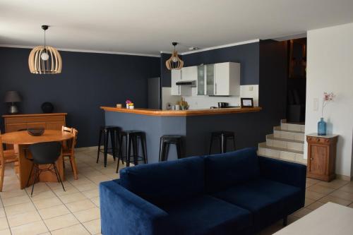 uma sala de estar com um sofá azul e uma cozinha em La Bâtie - Terrasse avec Vue imprenable sur le Rhône, 3 chambres, 3 salles de bain em Tain-lʼHermitage