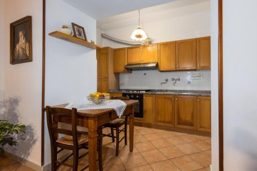 a kitchen with wooden cabinets and a table with chairs at Enchanting Flat with Patio in Abbadia a Isola in Monteriggioni