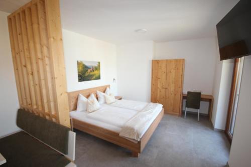 Dormitorio con cama, escritorio y TV en Residence Karpoforus en Laces