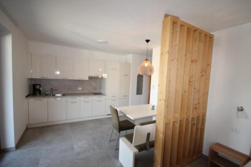 una cocina con armarios blancos y una mesa con sillas. en Residence Karpoforus en Laces