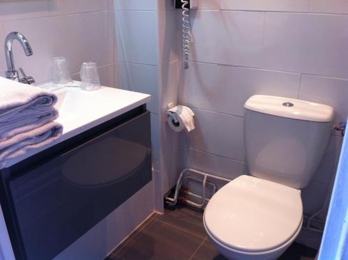 La salle de bains est pourvue de toilettes blanches et d'un lavabo. dans l'établissement Grand Hôtel Magenta, à Paris