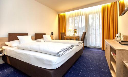a hotel room with two beds and a television at Hotel Bayern Vital in Bad Reichenhall