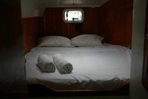 a bed with two towels on it with a window at On Y Va , Delightful 3 bedroom catarmaran, with skipper in Marmaris