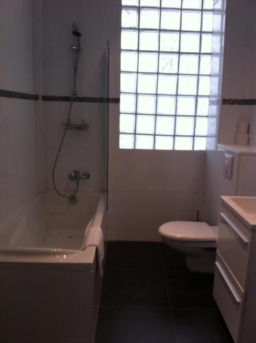 a bathroom with a tub and a toilet and a window at Grand Hôtel Magenta in Paris