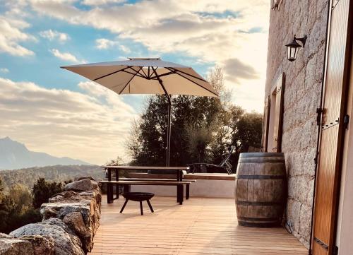 patio con tavolo da picnic e ombrellone di Maison de campagne, deux chambres, vue sur les montagnes a Sartène