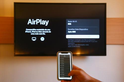 a person holding a cell phone in front of a tv at ibis Rio de Janeiro Botafogo in Rio de Janeiro