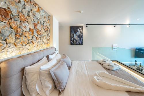 a bedroom with a stone wall and a bed with pillows at Pathos SeaSide Suites in Faliraki