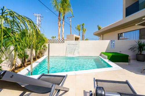 a swimming pool in the backyard of a house with two lawn chairs at Pathos SeaSide Suites in Faliraki