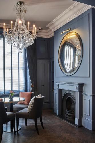 a living room with a chandelier and a fireplace at The Tophams Hotel in London