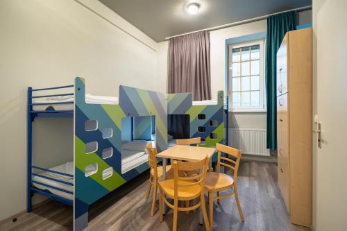 a room with a table and chairs and a bunk bed at a&o Salzburg Hauptbahnhof in Salzburg