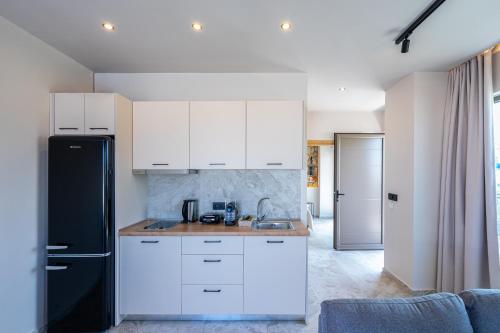 a kitchen with white cabinets and a black refrigerator at Pathos SeaSide Suites in Faliraki