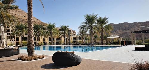 een zwembad van het resort met palmbomen en een zwarte bal bij ONE Elegant Apartment in Muscat Bay 02 in Muscat