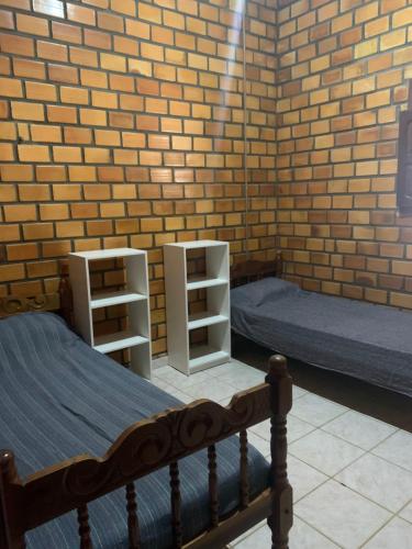 a bedroom with two beds and a brick wall at Cifa & Alê Hospedaria in Conde