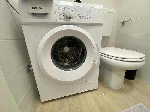 baño con aseo y lavadora blanca en Solemare Federica, en Lignano Sabbiadoro