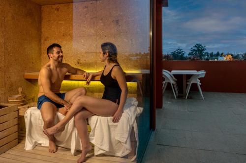 a man and a woman sitting on a bed at Vitoria Stone Hotel in Évora