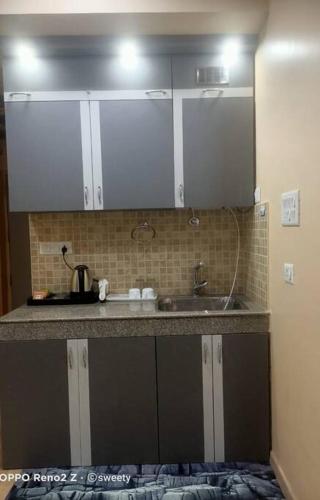 a kitchen counter with a sink and white cabinets at The Origin Suites DLF MY PAD in Lucknow