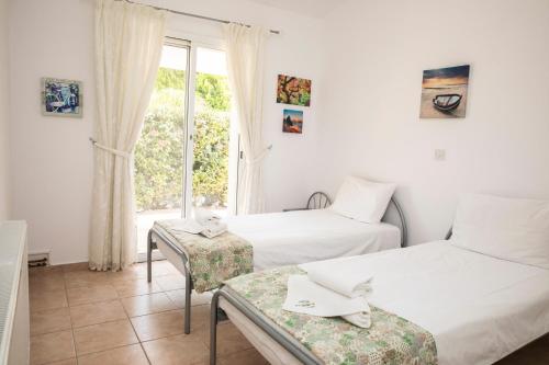 2 Betten in einem Zimmer mit Fenster in der Unterkunft Villa Salieri: Coral Bay villa with private pool in Peyia