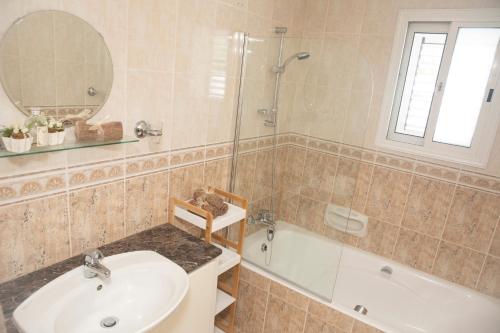 ein Badezimmer mit einem Waschbecken, einer Dusche und einer Badewanne in der Unterkunft Villa Salieri: Coral Bay villa with private pool in Peyia