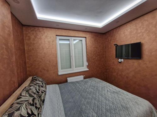 a bedroom with a bed and a flat screen tv at Apartman Dionis in Užice