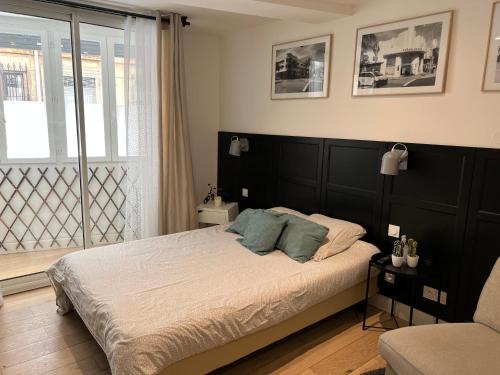 a bedroom with a bed with a black headboard and a window at Lou Pitchoun in Aix-en-Provence