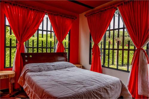 1 dormitorio con cortinas rojas, 1 cama y 2 ventanas en Estancia Rosa de Jericó Campestre, en Guaduas