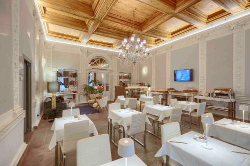 un restaurant avec des tables et des chaises blanches et un lustre dans l'établissement L'obelisque maison de luxe, à Rome