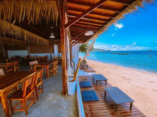 a restaurant on the beach with tables and benches at Wind Beach Resort in Koh Tao