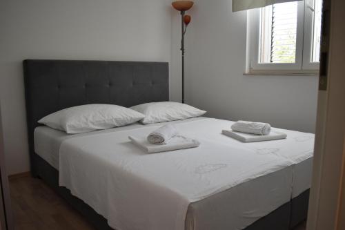 a white bed with two towels on top of it at Apartman DODO in Zadar