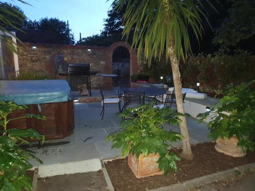 Winfrith Newburgh的住宿－Marley House Bed and Breakfast，一个带桌子、烧烤架和棕榈树的庭院