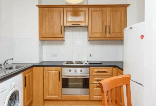 a kitchen with wooden cabinets and a stove and a refrigerator at Central Spacious Apartment w/ Balcony & City View in Dublin