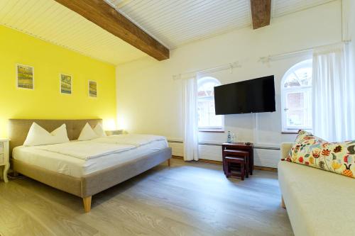a bedroom with a bed and a tv and a couch at Hotel Gut Schöneworth in Freiburg - Elbe