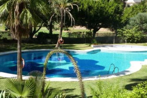 a blue swimming pool with palm trees in a yard at Cálido apartamento con gran terraza y vistas a 600 metros del mar in Benalmádena