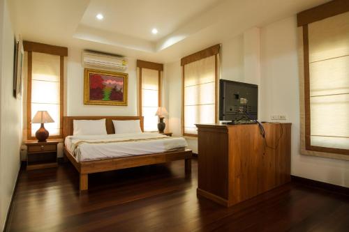 a bedroom with a bed and a flat screen tv at Thaihome Resort in Ban Bang Muang