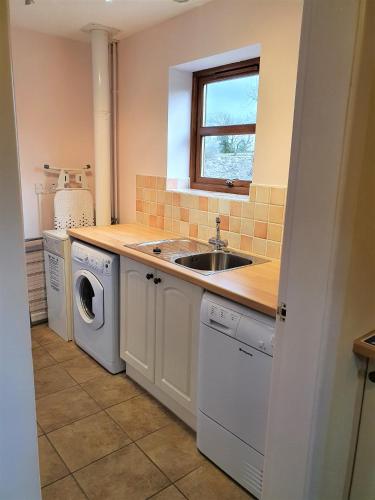 a kitchen with a sink and a washing machine at Fodol Cottages in Menai Bridge