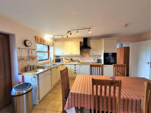 a kitchen with white cabinets and a table with chairs at Fodol Cottages in Menai Bridge