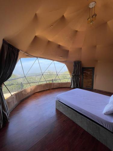 a bedroom with a bed and a large window at ببالز Ajloun عش وسط الطبيعة - ِAjloun Bubbles Live amid nature in Ajloun