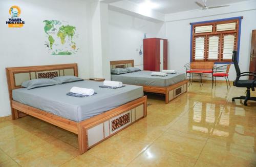 a bedroom with two beds and a table and chairs at Yaarl Hostels in Jaffna