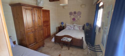 una piccola camera con letto e armadio in legno di Gizimina B&B by VeroSole a Xagħra