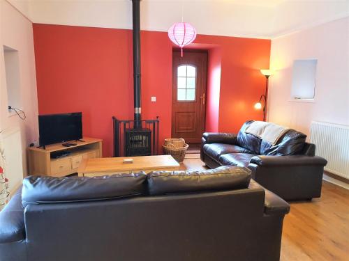 a living room with two leather couches and a tv at Fodol Cottages in Menai Bridge