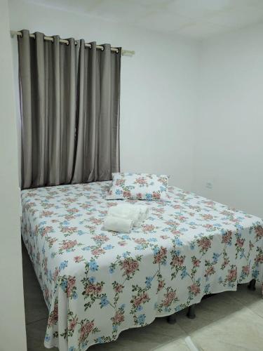 a bedroom with a bed with a floral bedspread at Pousada Beach Claudia in Maragogi