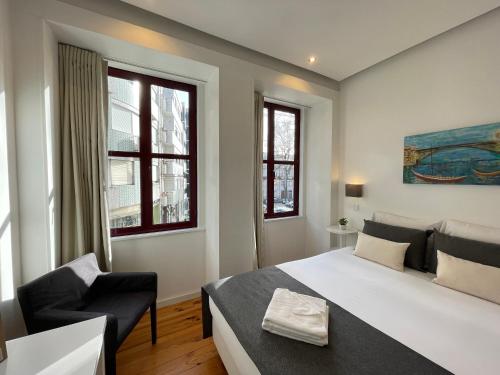 a bedroom with a large white bed and a chair at MyStay Porto Centro in Porto